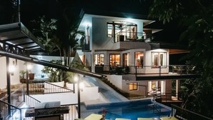 Una casa moderna de dos pisos con piscina, mobiliario exterior y zona de barbacoa.