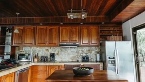Una cocina moderna con armarios de madera, salpicadero de piedra y electrodomésticos de acero inoxidable.