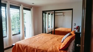 Un dormitorio con dos camas, ventanas amplias y vistas al paisaje verde exterior.