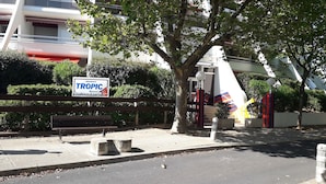 A residential area with a Tropic sign, a bench, and a tree.