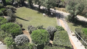 A well-maintained garden with various shrubs and trees, a paved walkway, and a sign indicating a parking area.