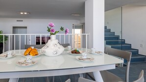 Un comedor moderno con una mesa de vidrio, sillas blancas y un jarrón con flores.