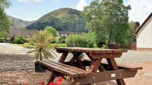 Une table de pique-nique en bois, installée dans une cour, avec une chaîne de montagnes en arrière-plan.