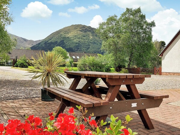 A wooden picnic table in a courtyard with a mountain backdrop.
