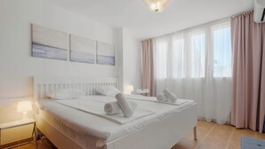 Une chambre à coucher moderne avec un grand lit, deux tables de chevet, une petite table et un luminaire au plafond.