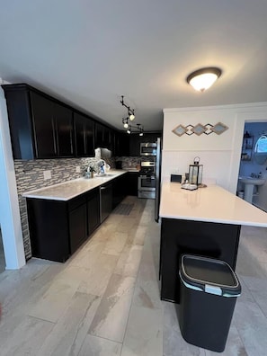 A modern kitchen with dark cabinets, a light countertop, and a built-in oven. - Walk to everything! NEW Beautiful Home in Huron! (Huron)