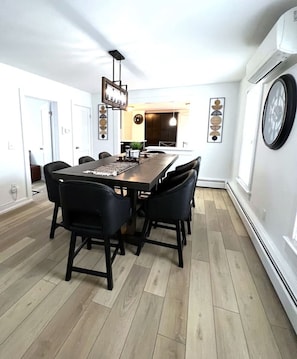 A modern dining area with a rectangular table, black chairs, and a hanging light fixture. - Walk to everything! NEW Beautiful Home in Huron! (Huron)