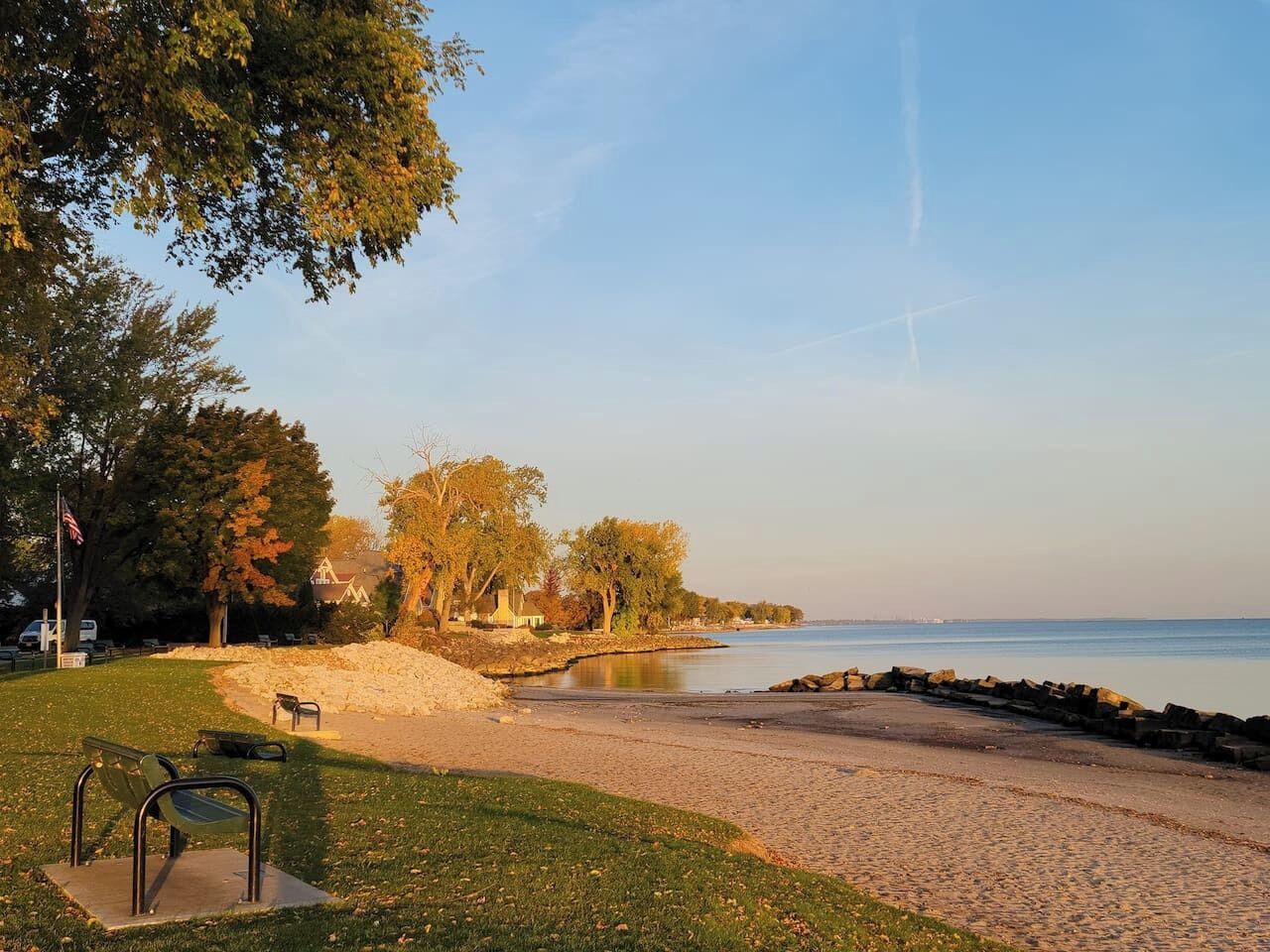 Une plage avec une promenade dallée, des bancs et des arbres.