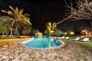 A swimming pool with a stone deck, surrounded by lounge chairs and palm trees. - Agrology Lux (Rhodes)
