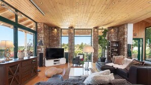 A spacious living area with a stone wall, a television, a sofa, and a coffee table. - Agrology Lux (Rhodes)