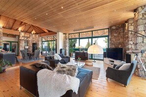 A spacious living area with a stone wall, wooden ceiling, and a fireplace.