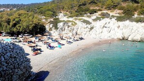 A beach with clear turquoise water, white sandy shore, and a rocky cliff. - Agrology Lux (Rhodes)