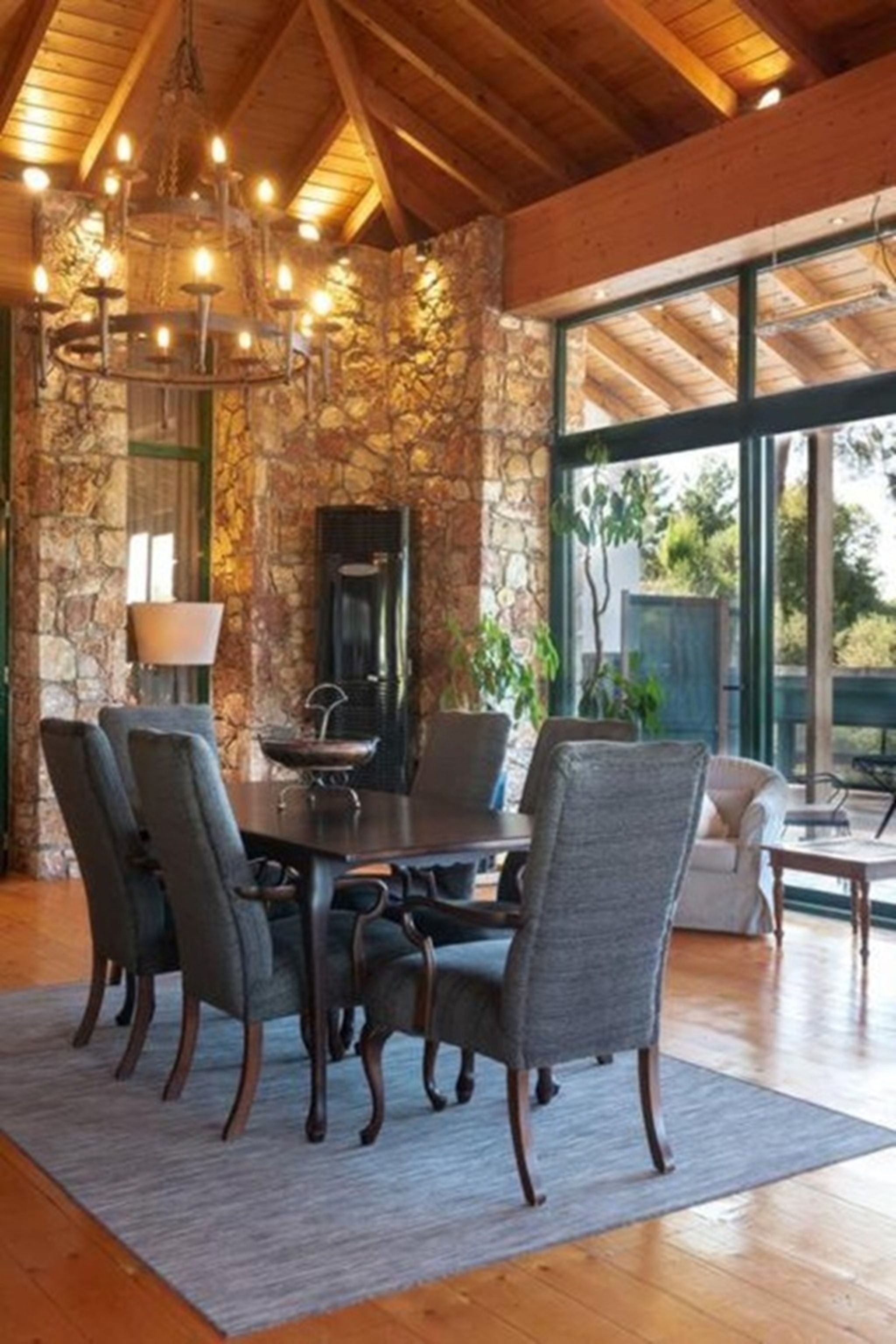 A dining area with a stone wall, a chandelier, and a large window.