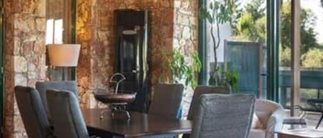 A dining area with a stone wall, a chandelier, and a large window.