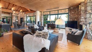 A spacious living area with a stone wall, wooden ceiling, and a fireplace. - Agrology Lux (Rhodes)