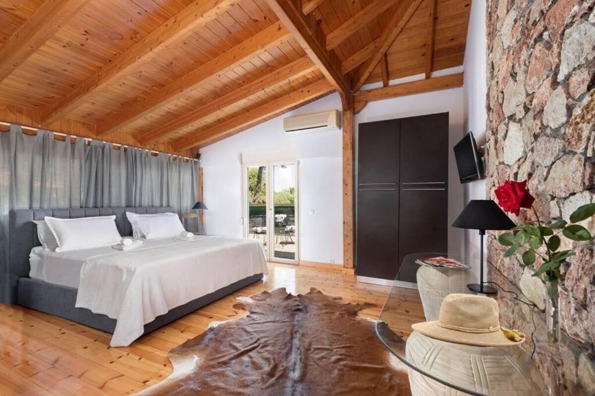 Un dormitorio con cama, pared de piedra, televisor y alfombra de cuero.