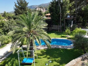 A swimming pool surrounded by lush greenery, a swing, and a stone wall. - Agrology Lux (Rhodes)
