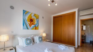 Ein Hotelzimmer mit einem großen Bett, zwei Nachttischlampen, einem Holzschrank und einem Blumenbild an der Wand.