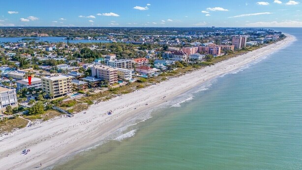Eine Küstenstadt mit einem weiten Sandstrand, Gebäuden entlang der Uferlinie und freier Sicht auf den Ozean.