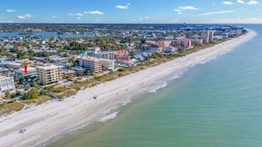 Un paysage urbain côtier avec une vaste plage de sable, des bâtiments le long de la côte et une vue dégagée sur l’océan.