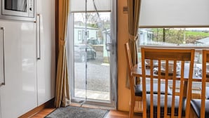 A kitchen with a built-in microwave, a sliding glass door leading to a balcony, and a dining area with a table and chairs. - 2 bedroom accommodation in Lamplugh (Lamplugh)