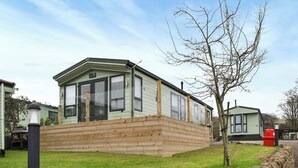 A green mobile home with a porch and a stone wall in front. - 2 bedroom accommodation in Lamplugh (Lamplugh)