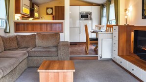 A compact living space with a sofa, a small wooden table, a kitchen area with a microwave and refrigerator, and a television. - 2 bedroom accommodation in Lamplugh (Lamplugh)