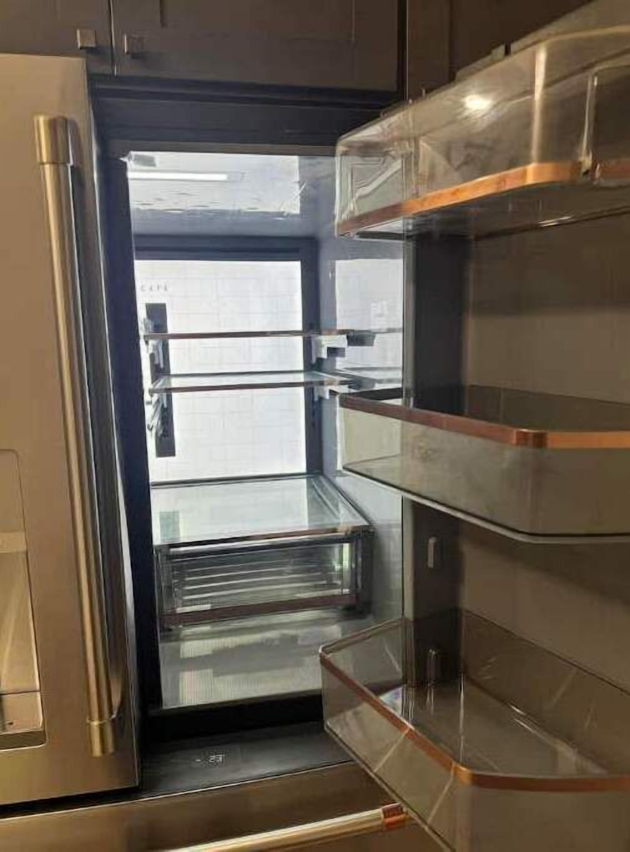 Una cocina moderna con electrodomésticos de acero inoxidable, un refrigerador con puerta de vidrio y un horno empotrado.