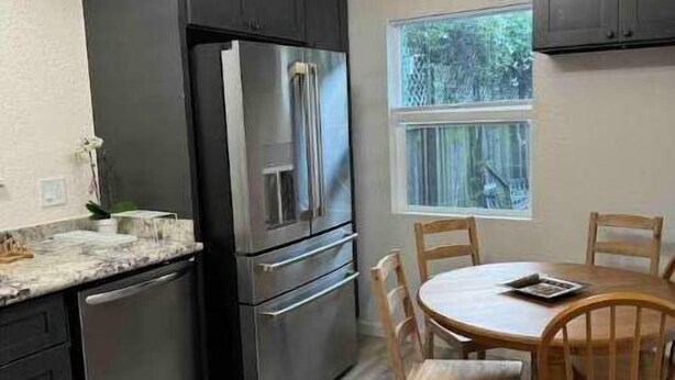 A modern kitchen with dark cabinets, stainless steel appliances, a gas stove, and a dining area with wooden chairs and a table.