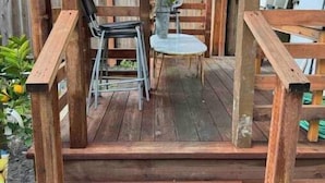 A wooden deck with a table and chairs, a small garden area, and a covered seating area.