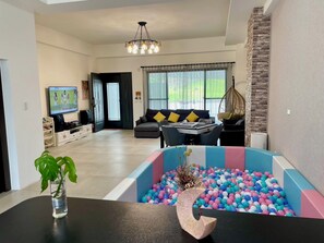 A spacious living area with a modern sofa, a dining table, and a ball pit. - YUTAI VILLA (Wujie)