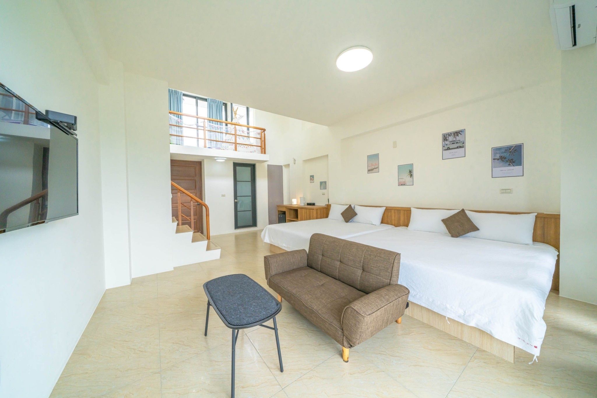 Habitación de hotel con cama, sofá, una mesita y una escalera que lleva a un nivel superior.