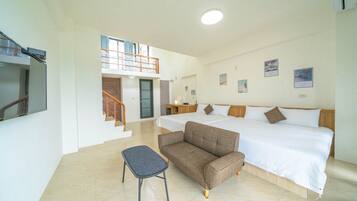 Habitación de hotel con cama, sofá, una mesita y una escalera que lleva a un nivel superior.
