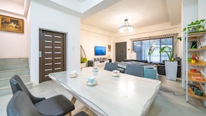 A modern dining area with a glass table, black chairs, and a television in the background. - YUTAI VILLA (Wujie)