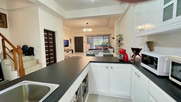 A modern kitchen with white cabinets, a black countertop, and a stainless steel sink. - YUTAI VILLA (Wujie)