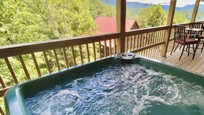 Boblebad på en træterrasse med udsigt til et bjerg og en skov.