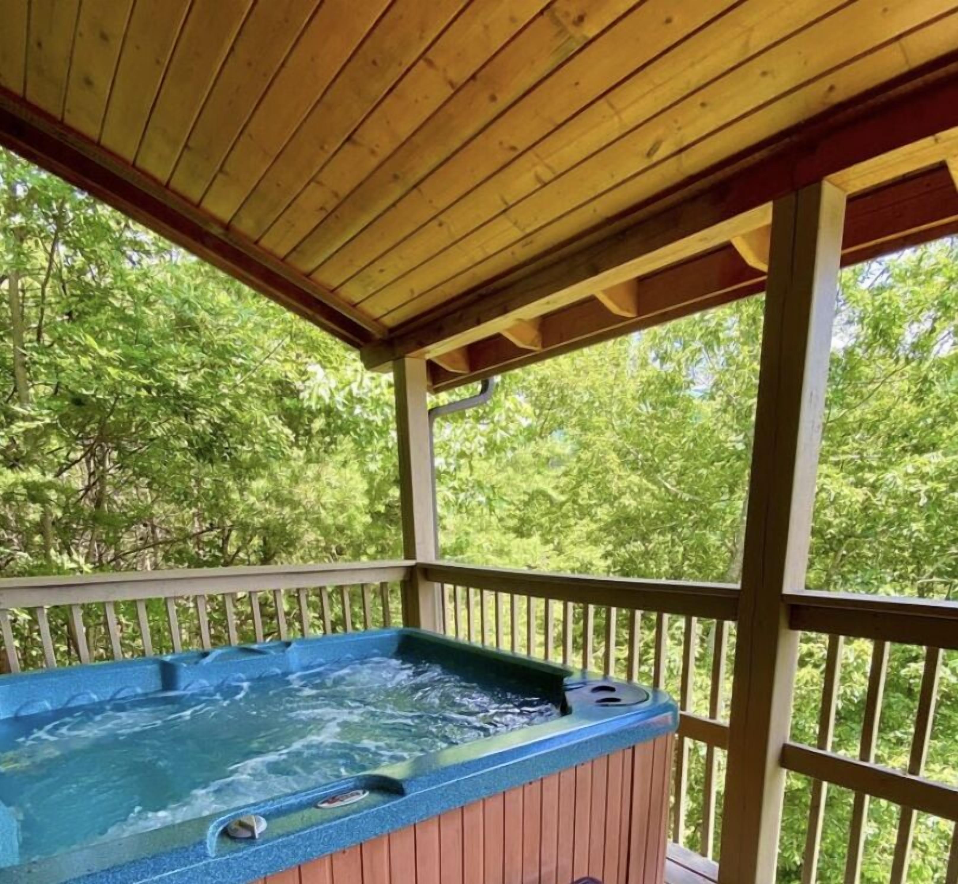 Een hottub onder een houten pergola, met uitzicht op bomen.