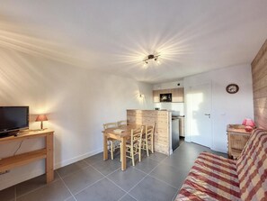 Espaço compacto com área de refeições, cozinha compacta e sofá.