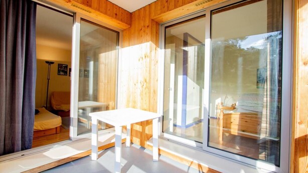 Een moderne kamer met grote schuifdeuren, een witte tafel en een houten vloer.