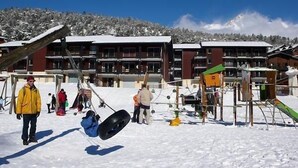 Een skigebied met een gebouw met meerdere verdiepingen en een skilift op de achtergrond.
