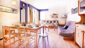 Een ruime woonkamer met een eettafel, stoelen, een bank en een televisie.