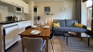 Um espaço compacto com cozinha compacta, área de refeições e espaço para sentar.