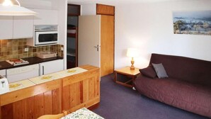 A compact living space with a kitchenette, a dining area, a sofa, and a painting on the wall. - 10m from ski slopes, 2nd floor, view mountain, balcony, 28m², Les Orres (Les Orres)