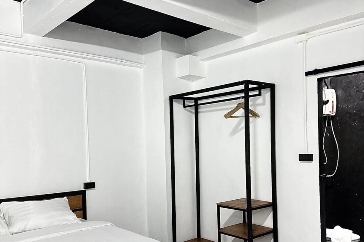A modern bedroom with a bed, a wooden wardrobe, and a black door.