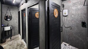 A modern bathroom with two shower doors, a sink, and a towel rack. - Sleep Owl Jomtien (Pattaya)