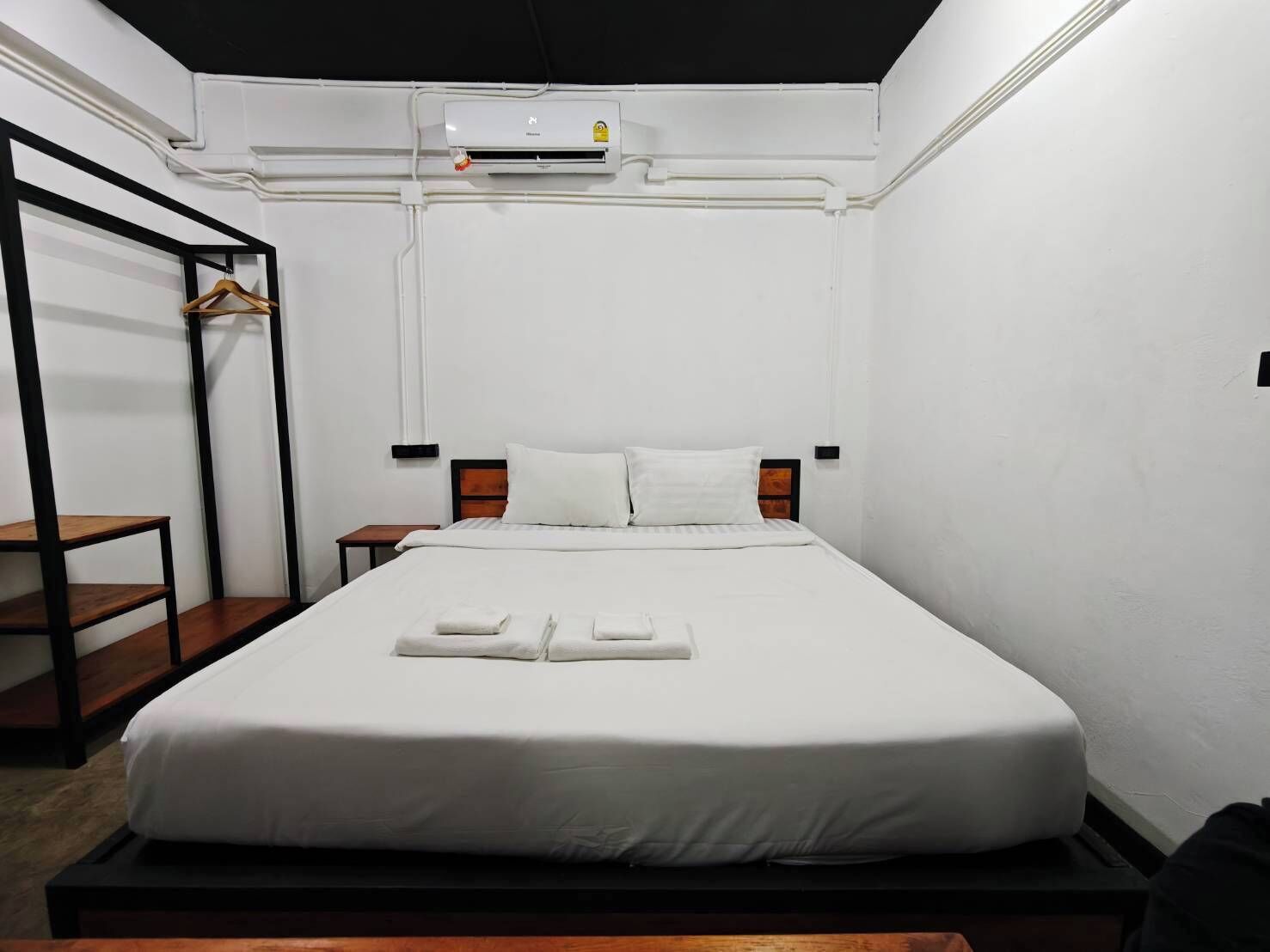 A single bed with a white mattress, a wooden headboard, and a bedside table.