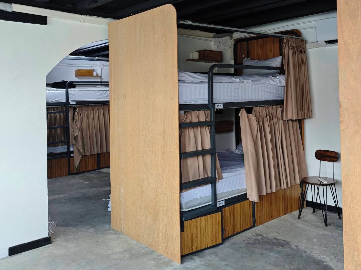 Quarto com beliche, painéis de madeira, uma pequena mesa e uma cadeira.