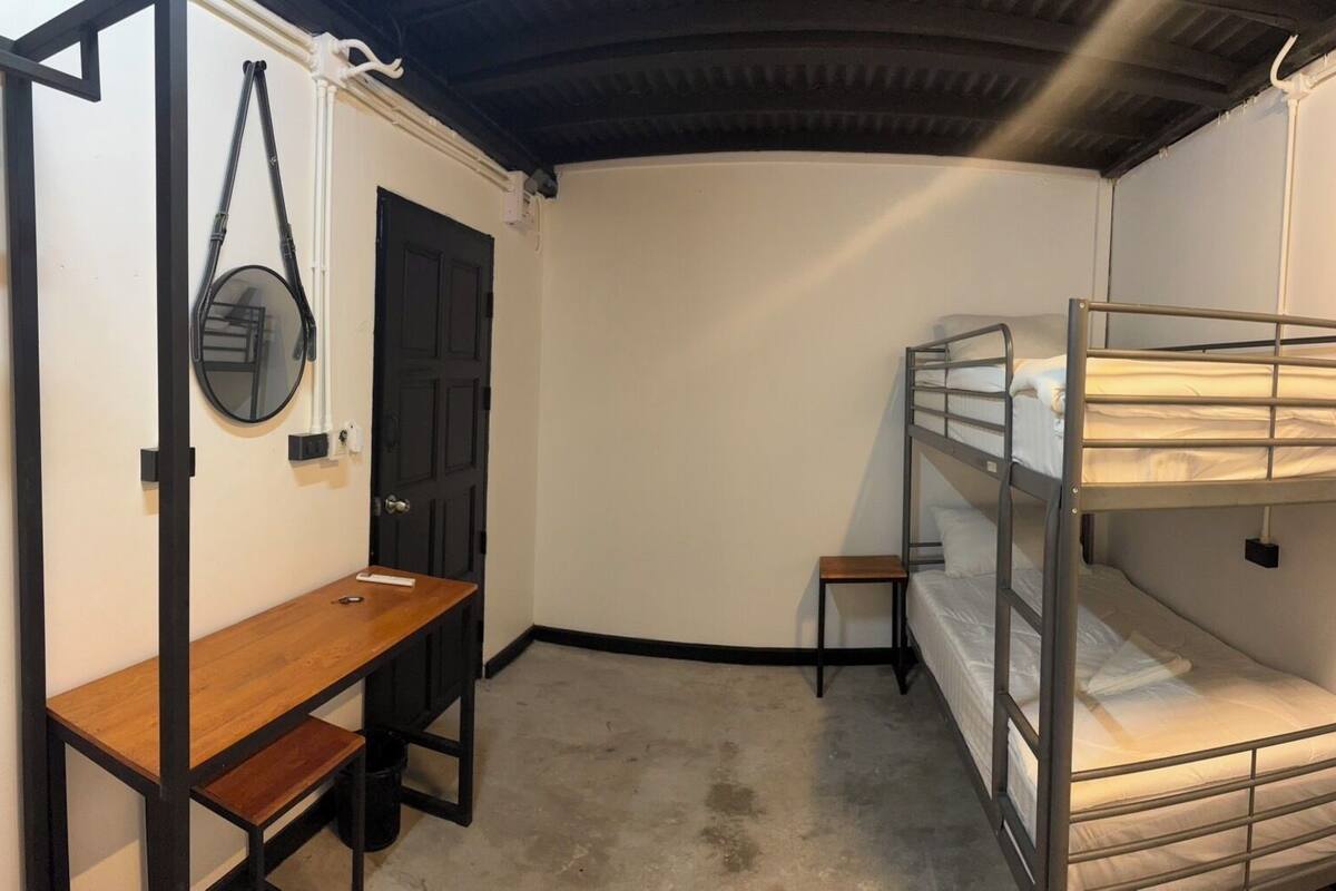 A compact room with bunk beds, a small wooden desk, and a door.