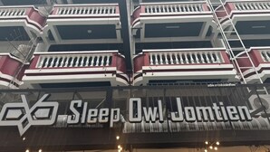 A multi-story hotel with balconies, a sign reading 'Sleep Owl Jomten,' and a staircase. - Sleep Owl Jomtien (Pattaya)