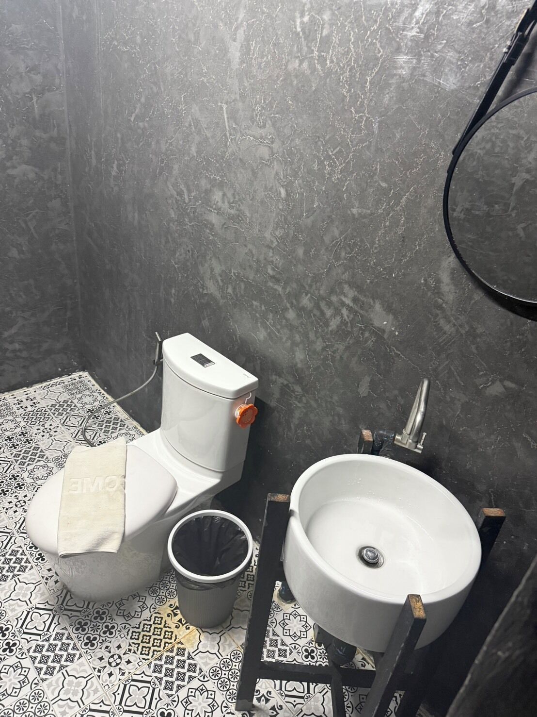Une salle de bain avec des toilettes, un lavabo et une petite poubelle.